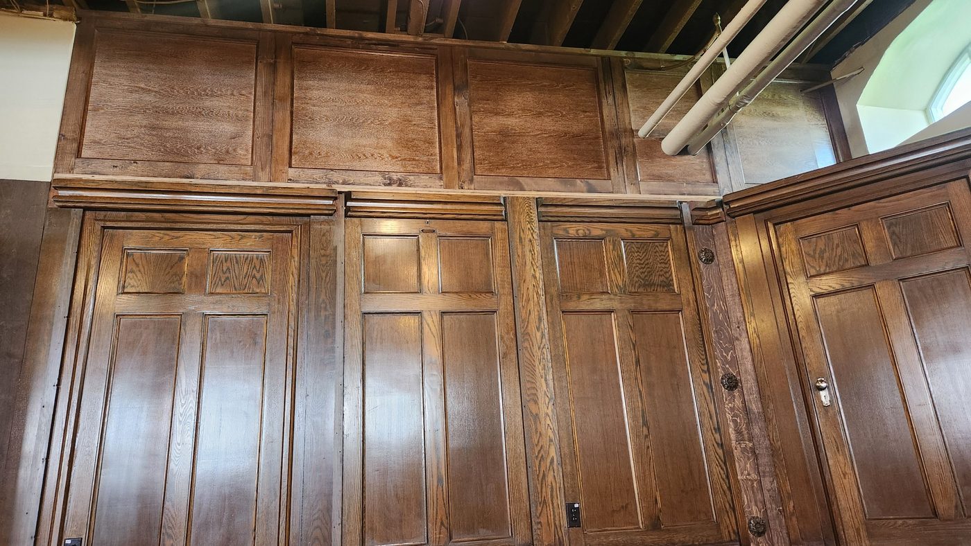 Wall of removable raised-panel storage cupboards above a stage, built by Staged Right Carpentry