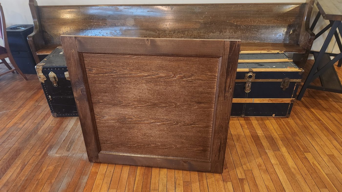 One finished raised-panel storage door standing on a wood floor, built by Staged Right Carpentry