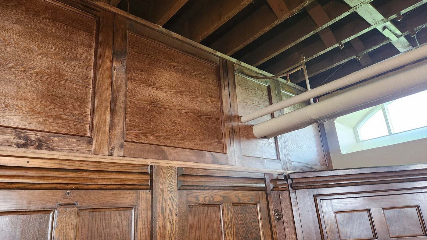 Removable raised-panel storage cupboards built around water pipes above a stage, by Staged Right Carpentry