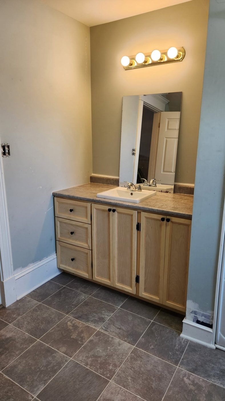 Finished custom bathroom vanity with mirror and lighting, built by Staged Right Carpentry