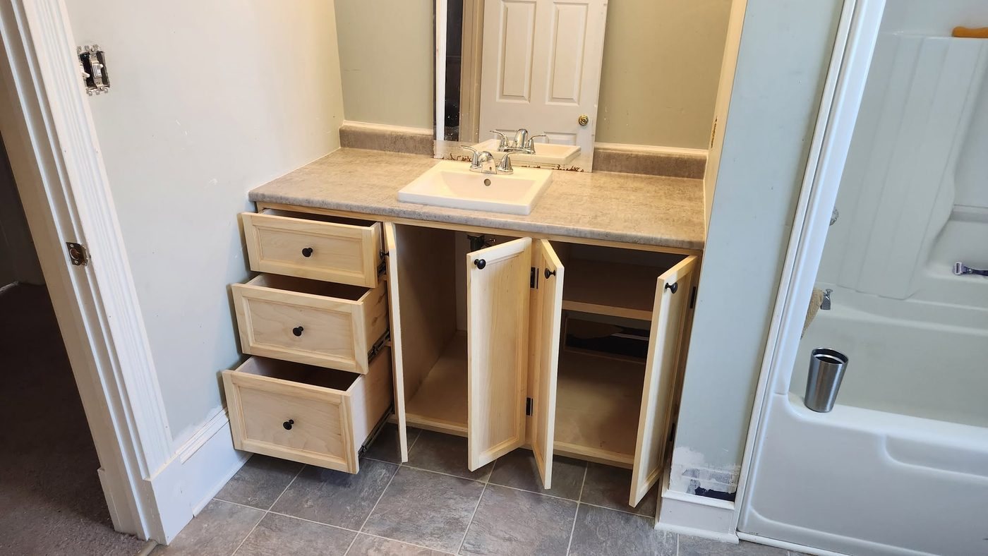 Custom bathroom vanity with drawers and cabinet doors open, built by Staged Right Carpentry